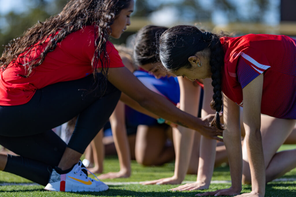 Children in red shirts doing push-ups outdoors during a sports activity.